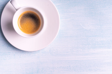 Espresso coffee in a white cup on a blue background. View from above. Space for text