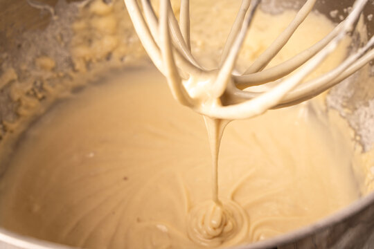 The dough is kneaded in a planetary mixer. The pancake or pie batter drips off the mixer whisk.