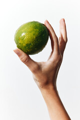 Person holding a green lime on a white background