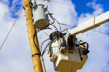 Bucket truck supports worker attending to electrical infrastructure on pole after hurricane