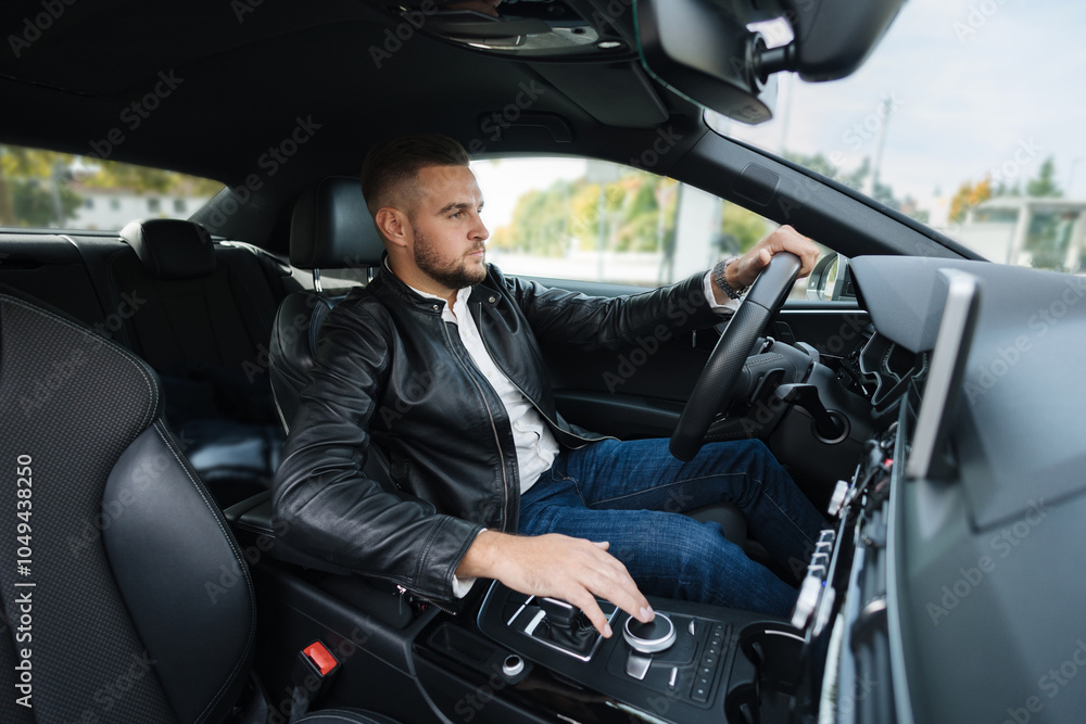 Wall mural success in motion. handsome young man in leather jacket driving a car. view from inside