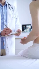 Obraz premium Doctor and patient. Physician is making notes on a clipboard while patient woman is describing something. Pediatrician, medicine concept