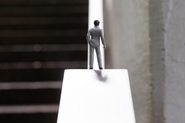 A male figurine in a business suit standing on a straight uphill slope - an image of life and...