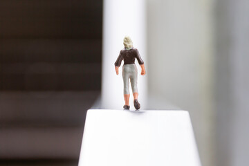 A female figurine in a business suit standing on a straight uphill slope - an image of life and...