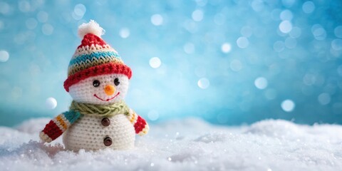 Fototapeta premium A cheerful knitted snowman with a red and blue hat and scarf stands proudly in a field of pristine white snow, the soft blue bokeh background creating a winter wonderland.