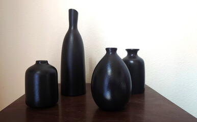 four empty boho black vases against a white background