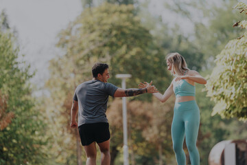 Fototapeta premium Two friends are exercising together in a scenic park on a bright sunny day, sharing a moment of joy and fitness. The lush surroundings add to the refreshing outdoor atmosphere.