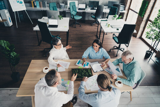 Photo high view of teamwork startup partners people sit table work together comfortable nice creative startup office loft room interior