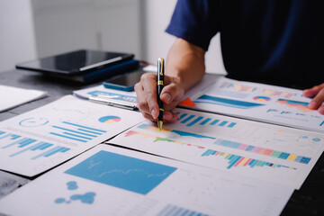 businessman sits at his office desk, analyzing financial documents and graphs on his laptop. paperwork, calculator, and charts, he strategizes investments, audits, tax planning for success.