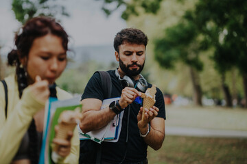 A group of multicultural students taking a break from classes, enjoying ice cream together in a...