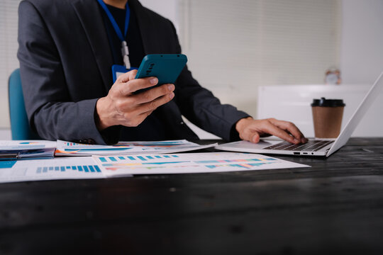 businessman sits at his office desk, analyzing financial documents and graphs on his laptop. paperwork, calculator, and charts, he strategizes investments, audits, tax planning for success. - Powered by Adobe