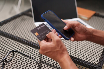 cheerful businessman sits at his desk, using a laptop to make an online purchase. With a credit card in hand, he connects to e-commerce, enjoying seamless technology and finance solutions.