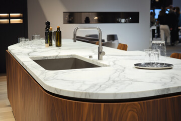 The modern kitchen with curved white marble countertops is in harmony with the overall architecture of the room.