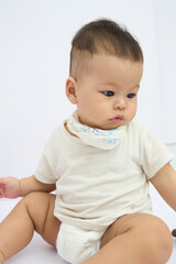 A Baby Handsome Sitting on the Floor with neck bib