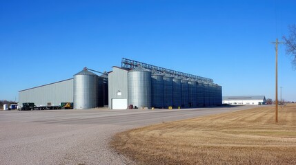 A silo warehouse facility with massive metal silos, clean industrial surroundings, and an open yard, set under a bright, cloudless sky.