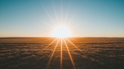 Glowing sun setting in a clear sky, casting long shadows over a flat landscape, evoking feelings of calm and the day's end.