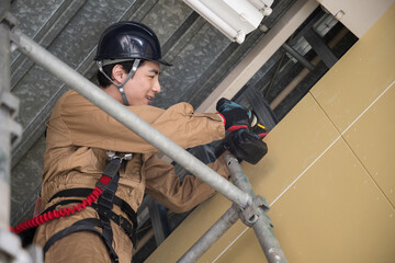 People in work clothes with safety belts repairing with scaffolding