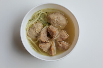 Indonesian meatballs, big and small meatball, served with noodles and broth. On white bowl, isolated on white background. Small portion. Flat lay or top view