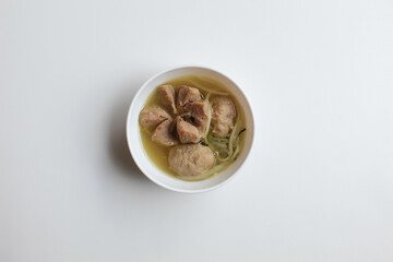Indonesian meatballs, big and small meatball, served with noodles and broth. On white bowl, isolated on white background. Small portion. Flat lay or top view