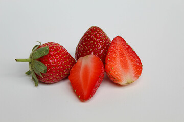 Whole and halved fresh strawberries, isolated on white background
