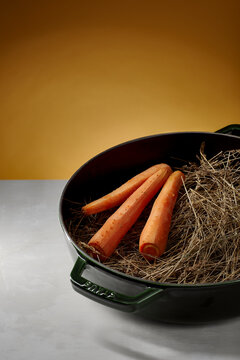 Carrots and hay nestle in a vintage pan