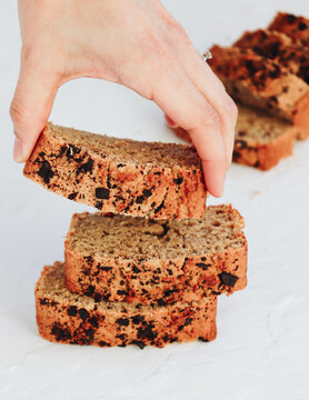 Hand picking up a slice of freshly baked chocolate chip bread