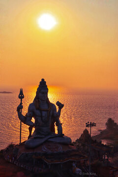 Lord Shiva statue near body of water during sunrise time