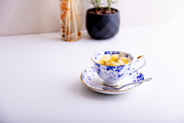 White and blue floral ceramic teacup on saucer with fruit pieces inside