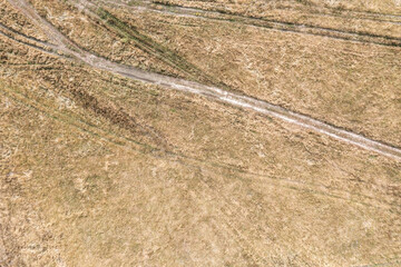 traces of car wheels on the dry grass of autumn field. top view from drone.