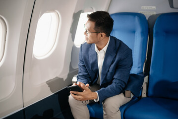 Young Asian executive excels in first class, multitasking with digital tablet, laptop and smartphone. Travel in style,