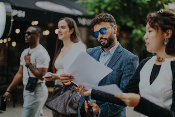 A diverse group of young professionals casually walking and reviewing business documents. They appear focused and engaged, suggesting a collaborative work environment. Ideal for themes of teamwork and