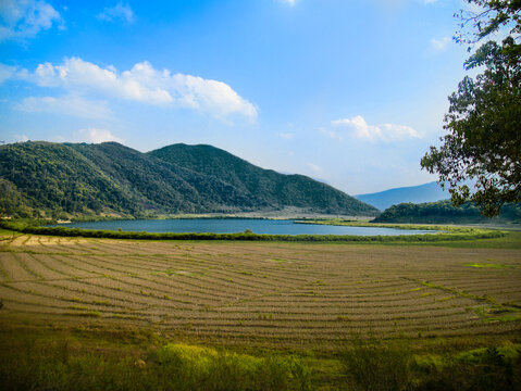 View of a lake surrounded by mountains and rice field although the rice has been harvested already. The lake is called Rih Dil in Myanmar although the Mizos of India consider it their own.