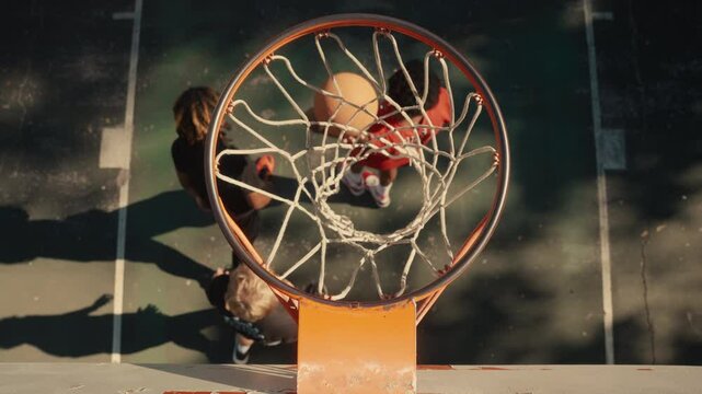 Young men playing basketball on an outdoor court on a sunny day