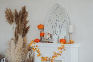 Autumn decor featuring pumpkins, candles, and dried flowers on a mantel in a bright room