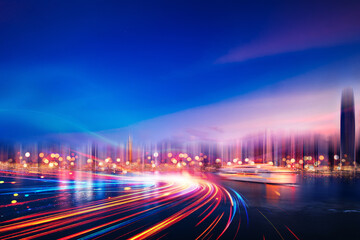 A city skyline at night with blurred light trails streaking through the foreground.