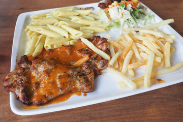 Indulge in a Delicious Grilled Chicken served alongside Pasta and Fries on a pristine White Plate