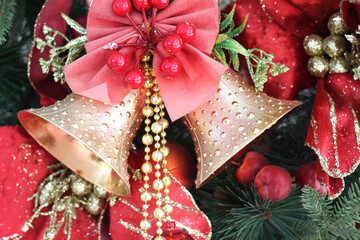 decorate christmas wreath bell with red bow hangs from a tree.