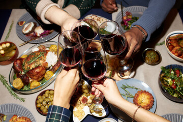 High angle shot of people clinking wine glasses celebrating Christmas together while sitting at...