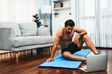 Athletic and sporty man frustrated due to hard difficulty of online body workout exercise session for fit physique and healthy sport lifestyle at home. Gaiety home exercise workout training concept.