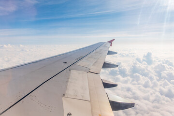 Fototapeta premium View from the airplane window at a beautiful cloudy sky and the airplane wing