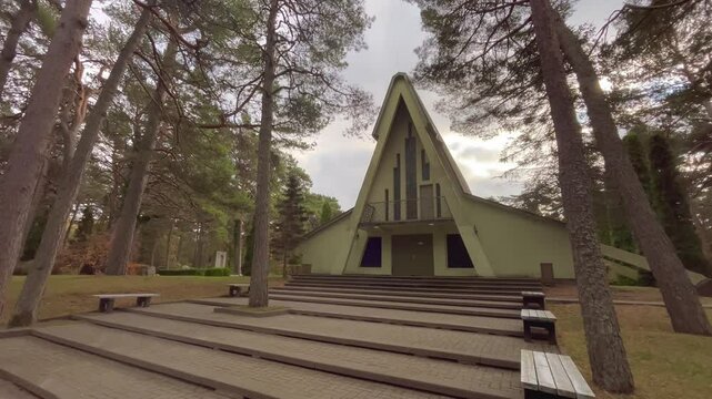Chapel in a serene forest cemetery with benches and steps leading to the entrance, located in the tranquil surroundings of Meža Kapi Cemetery in Ventspils, October day, static video