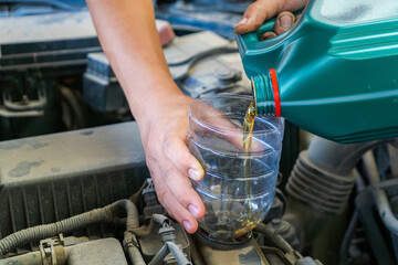 Close-up of engine oil being poured through a funnel made from a repurposed or recyled drinking water bottle.