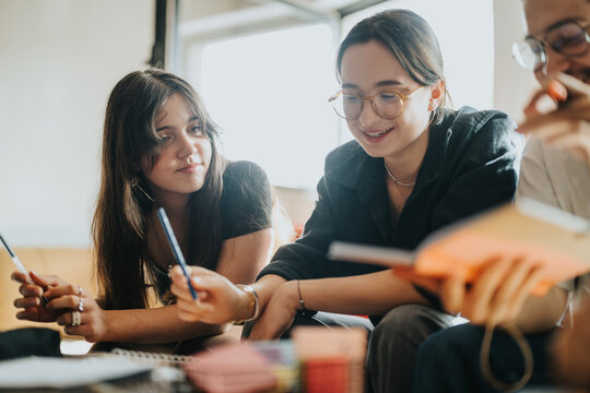 A group of students working together on a school task, sharing ideas and thoughts. They are engaged, using notebooks and pens, creating a collaborative learning environment.