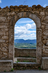 An old stone arch with a panoramic view of the village of Alvito, Italy.