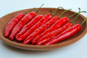 Some fresh big red chili, on wooden plate, isolated on white background