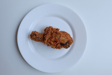 One crispy fried leg chicken, on white plate, isolated in white background, flat lay or top view