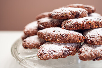 Italian Pane dei Morti cookies covered with powdered sugar, displayed on a glass plate in a close-up shot, background blurred in bokeh