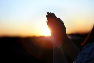 New Year sunrise rising sun background and shining light through praying christian hands, future hope and wish concept
