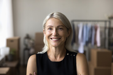 Headshot portrait of beautiful mid aged woman posing indoors with healthy toothy smile. Happy...