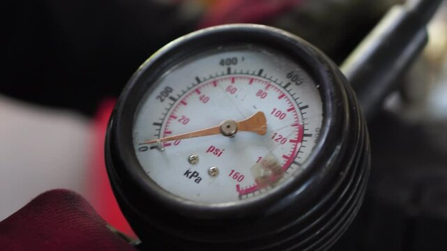 Auto repair shop.Mechanic inflating a car tire. Gas pumping of a car wheel. Car tire inflation. Car tire pressure check using air pressure guage.